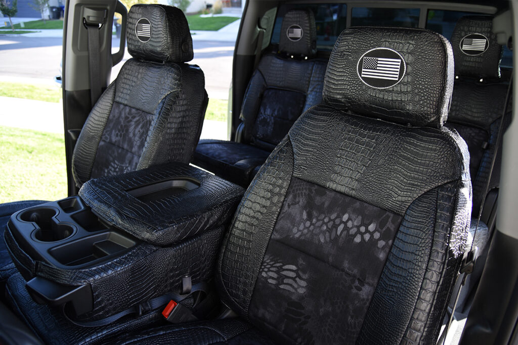 2025 GMC Sierra 3500 front Kryptek Typhon seat covers with Midnight Croc trim and center console cover