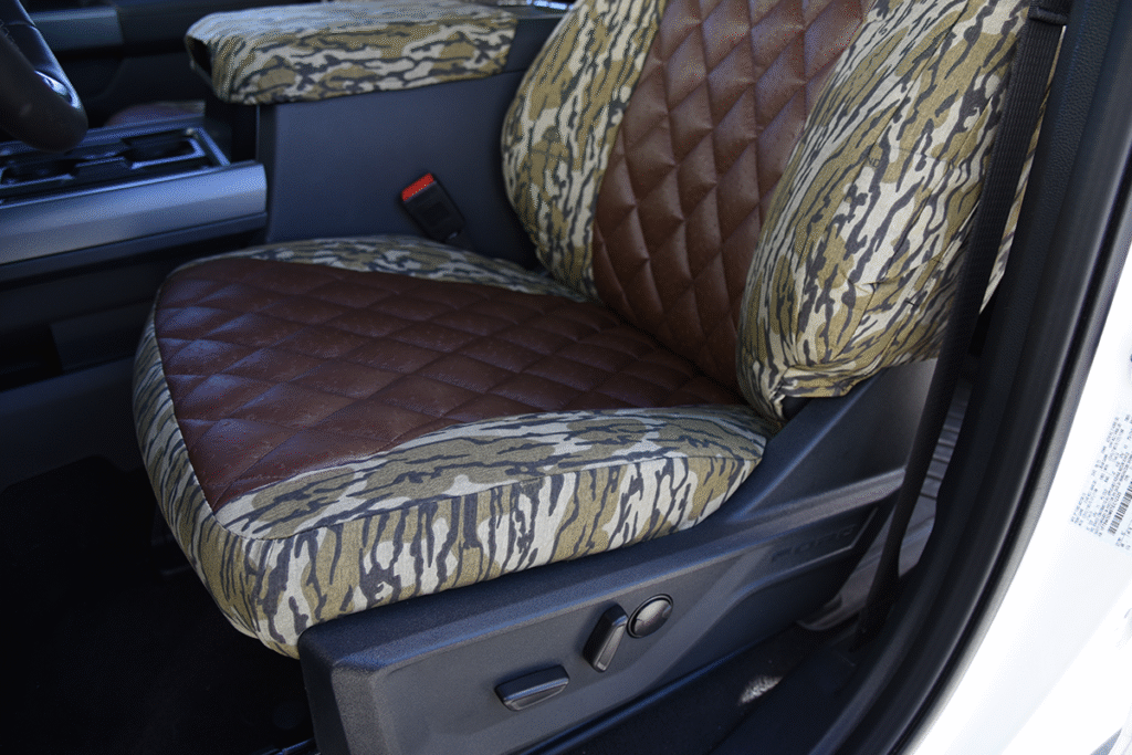 Seat bottom close-up of 2026 Ford F-350 seat covers in Brown Ostrich Diamond Stitch leatherette and Mossy Oak Bottomland camouflage
